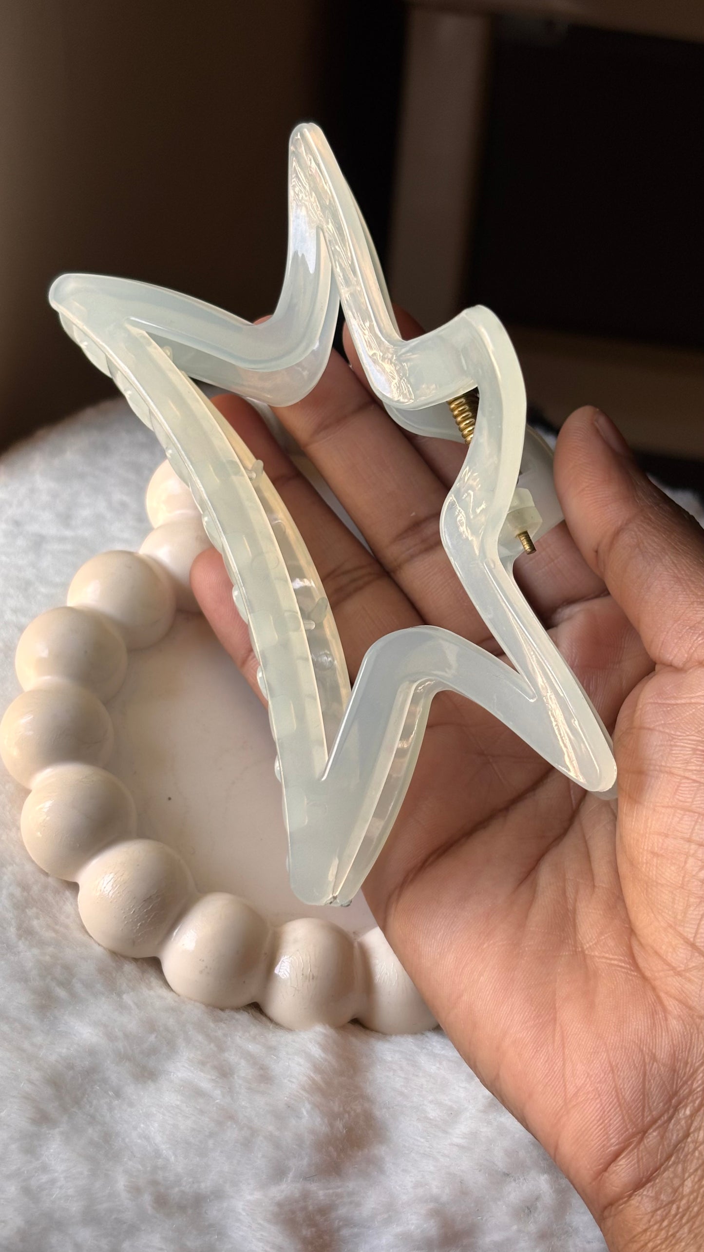 Clear plastic hair clip held in a hand with a blurred background