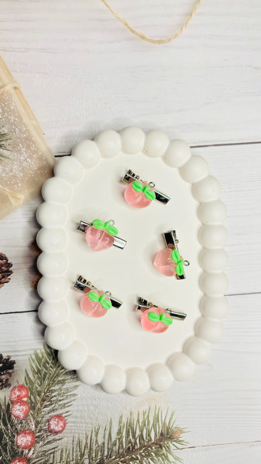 Set of hair clips with pink bases and green stems on a white surface.