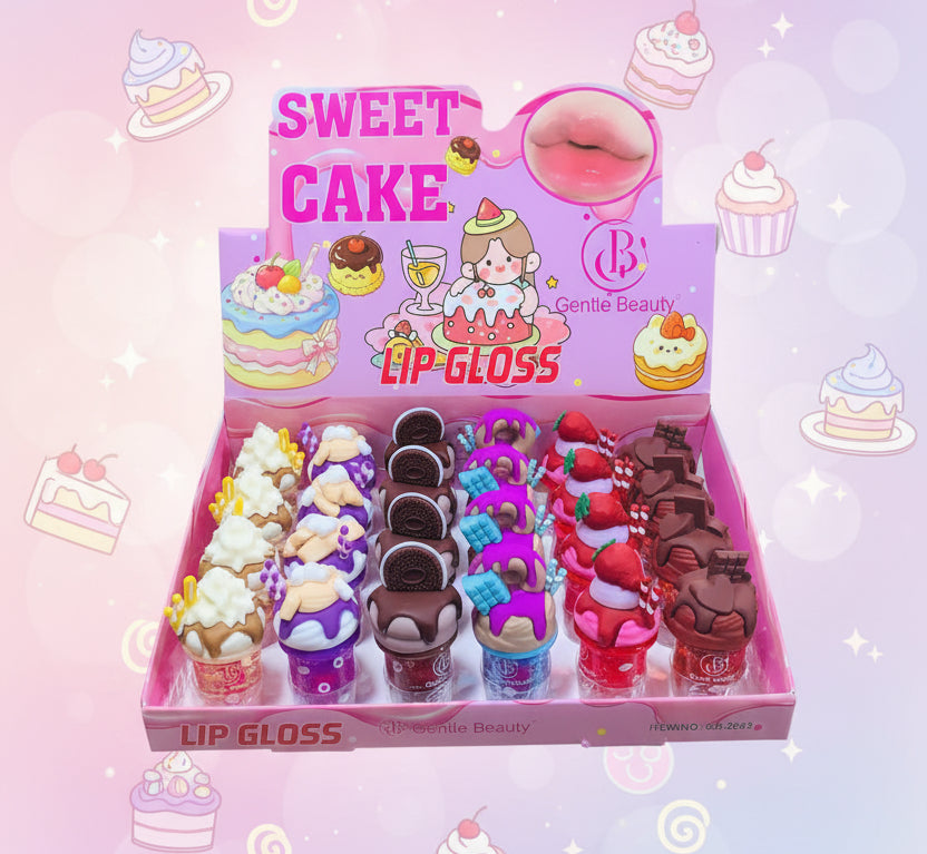 A pink display box of novelty lip glosses shaped like cupcakes and desserts, held in a hand. The packaging features cartoon graphics and the brand name 'Gentle Beauty'.