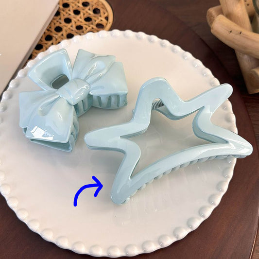 Two light blue hair clips on a white plate with a wooden background