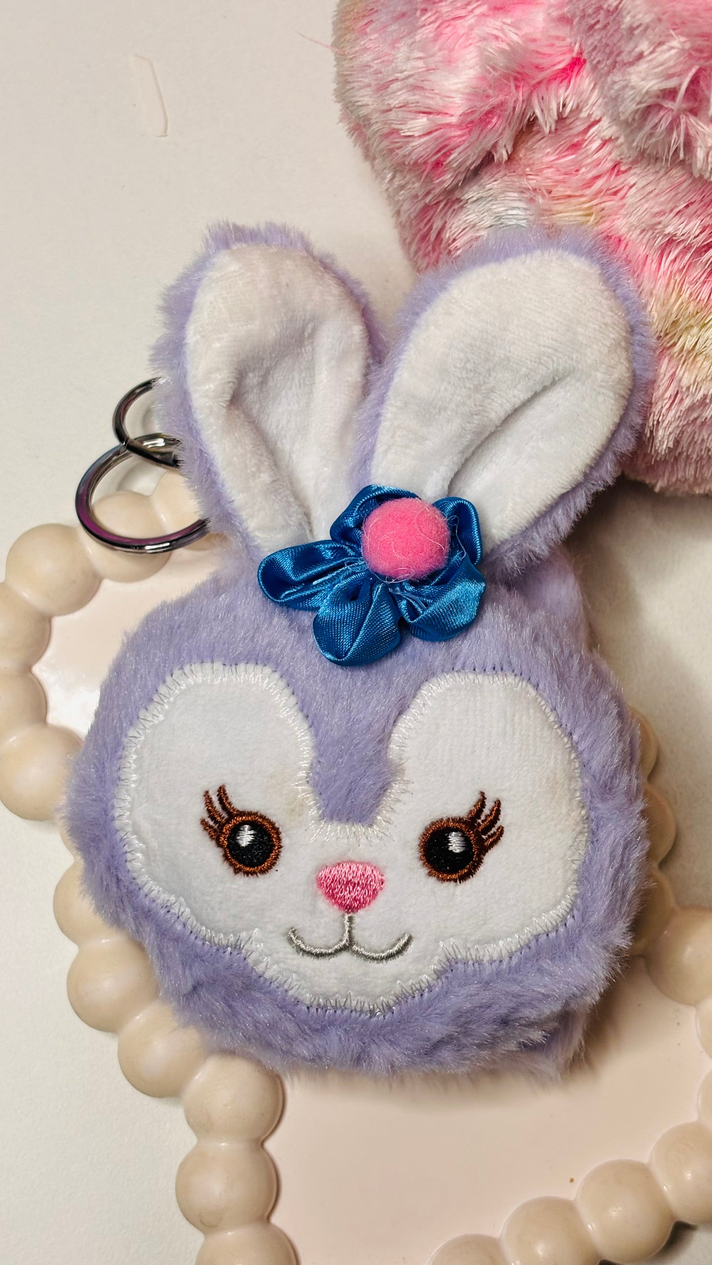 Fluffy bunny keychain with a blue bow on a white background
