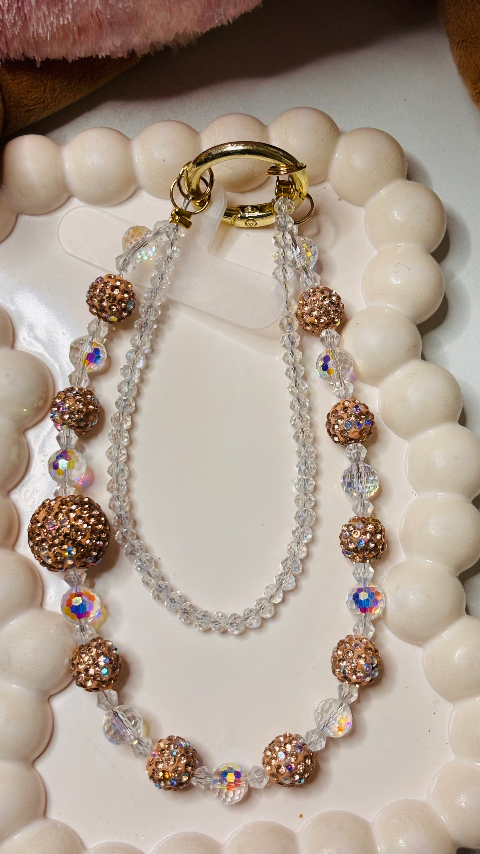 Phone charm with gold and clear beads on a white surface