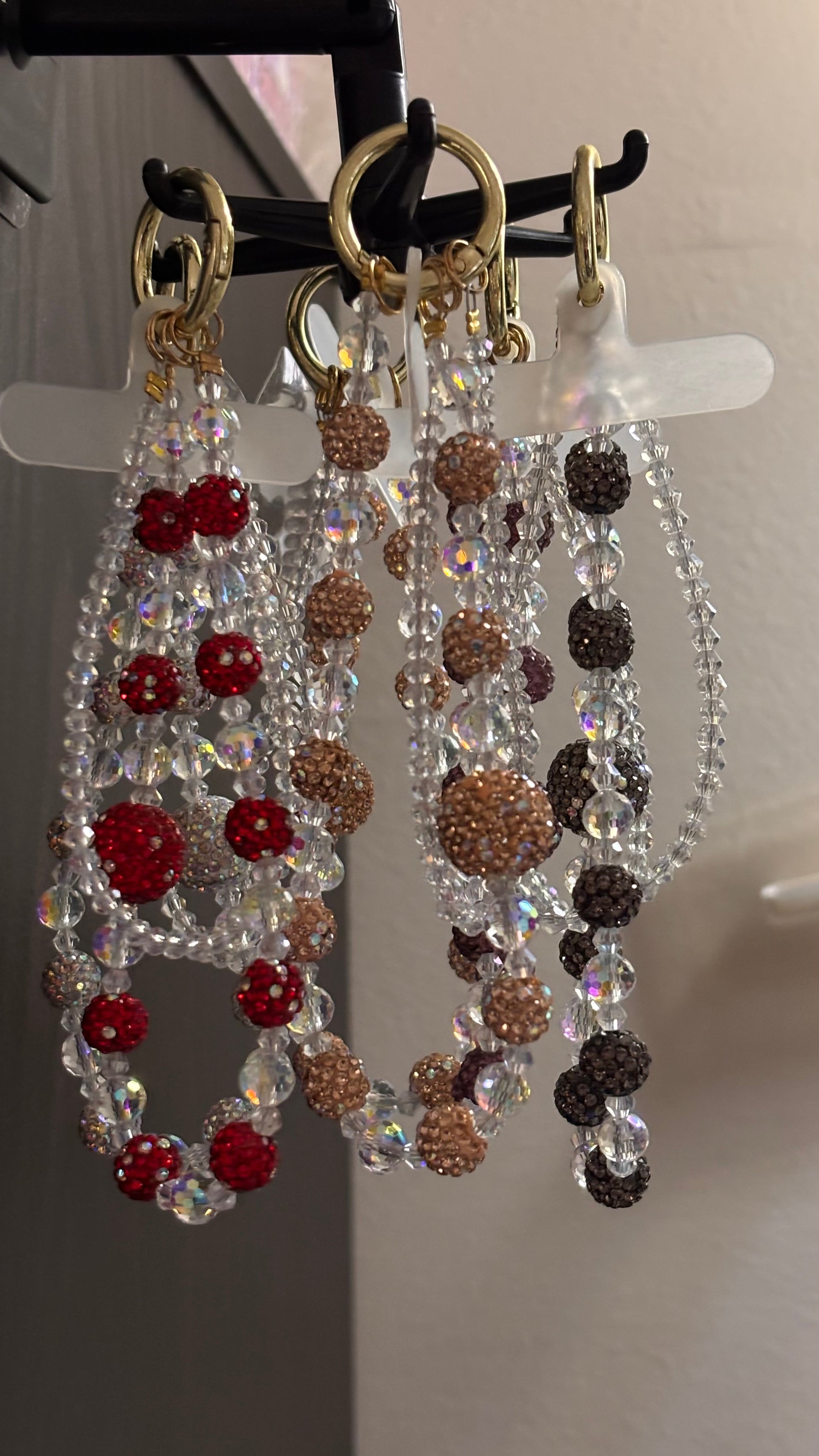 Beaded keychains with red and brown beads on a stand.