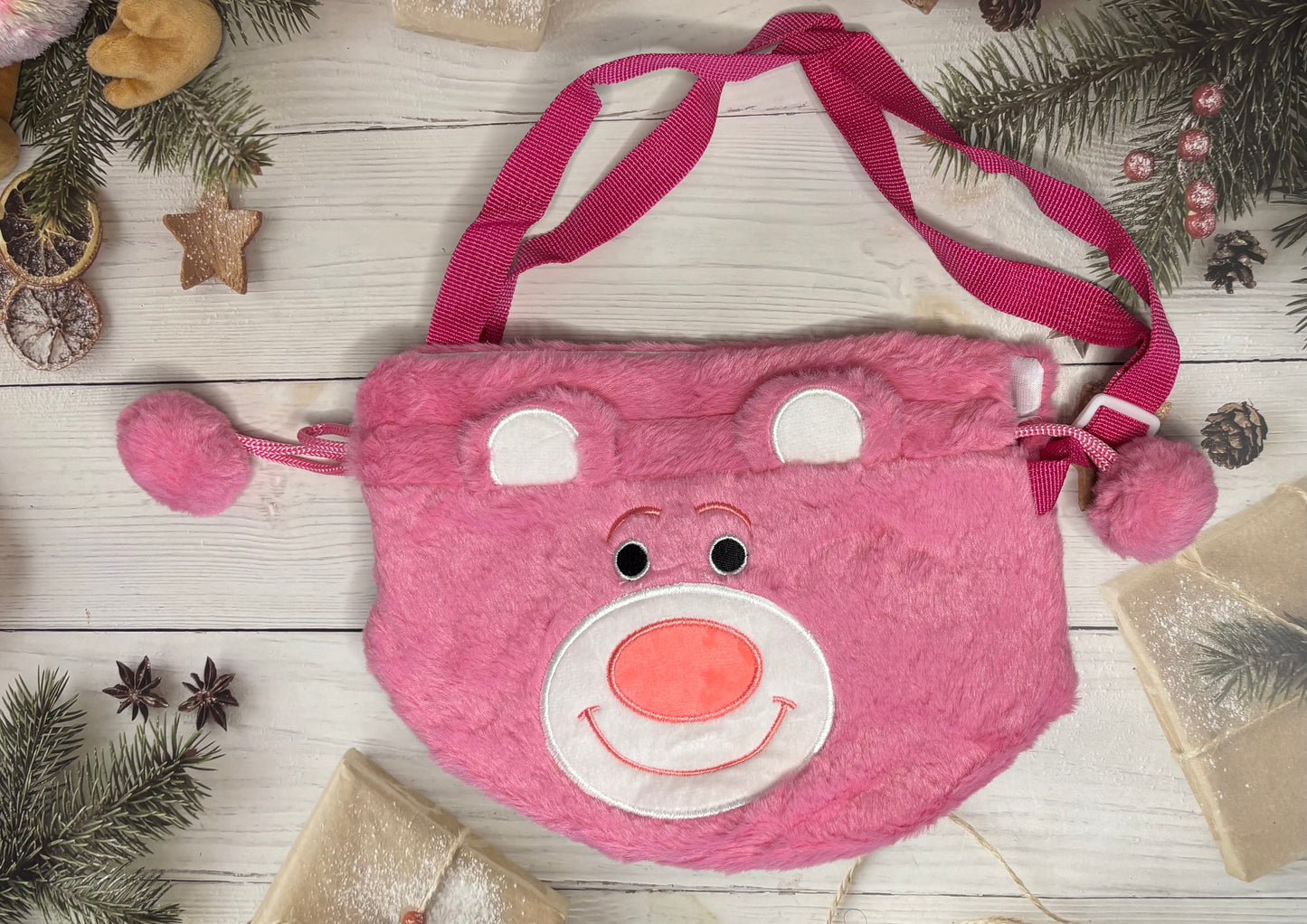 Pink children's bag with a face design on a wooden surface with Christmas decorations.
