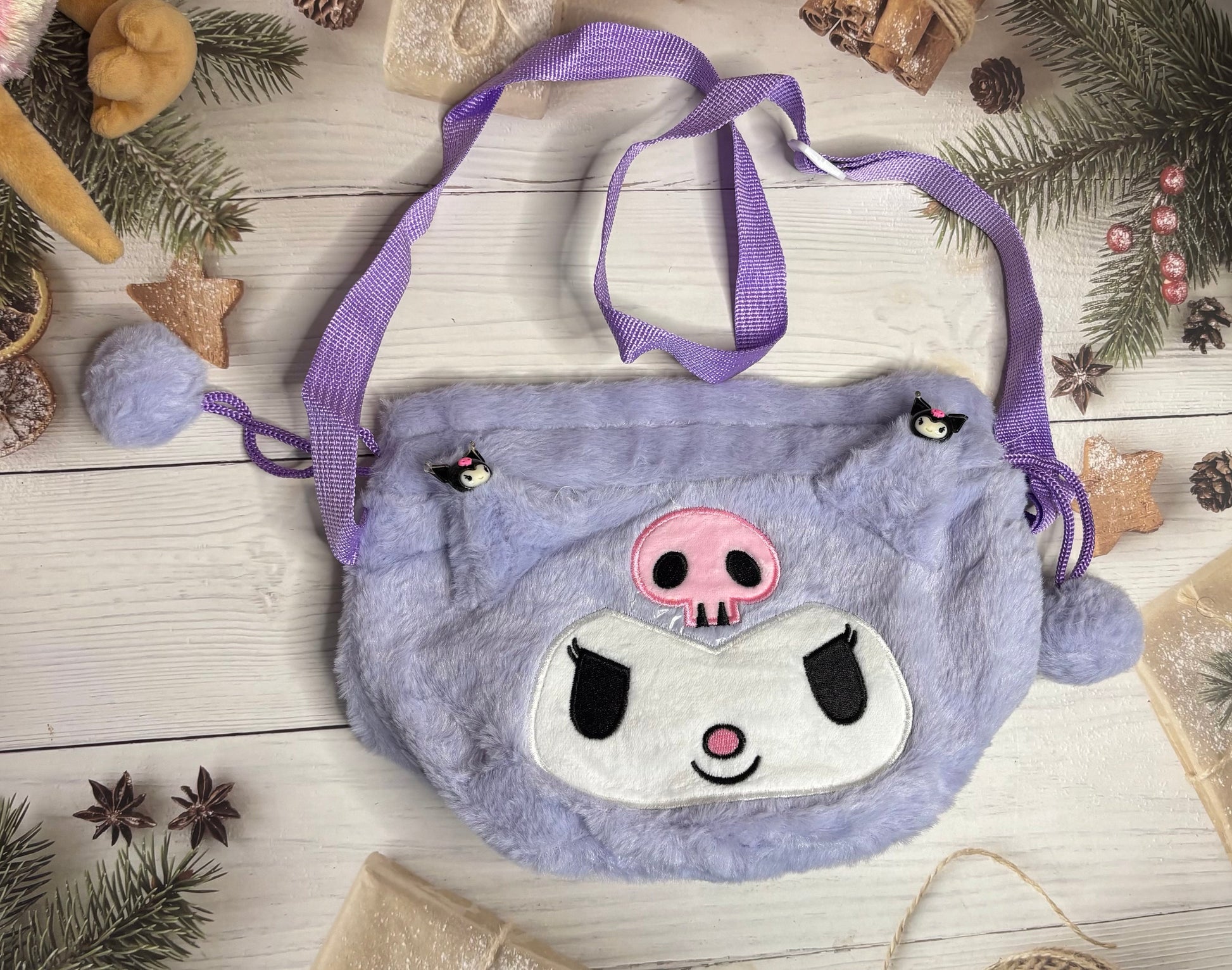 Blue sloth-shaped bag with a purple strap on a wooden surface with Christmas decorations.