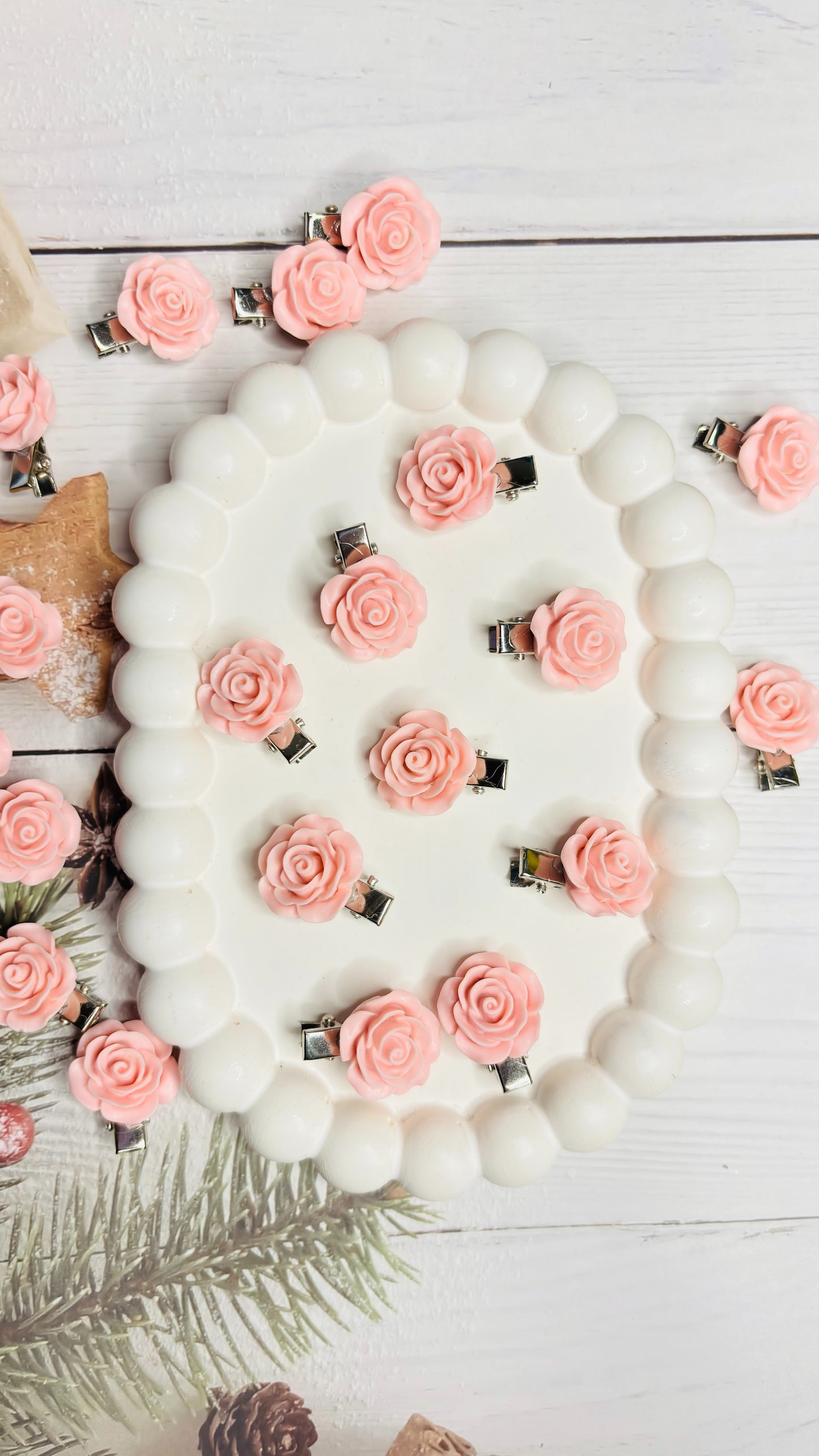 White beaded wreath with pink floral clips on a light wooden background