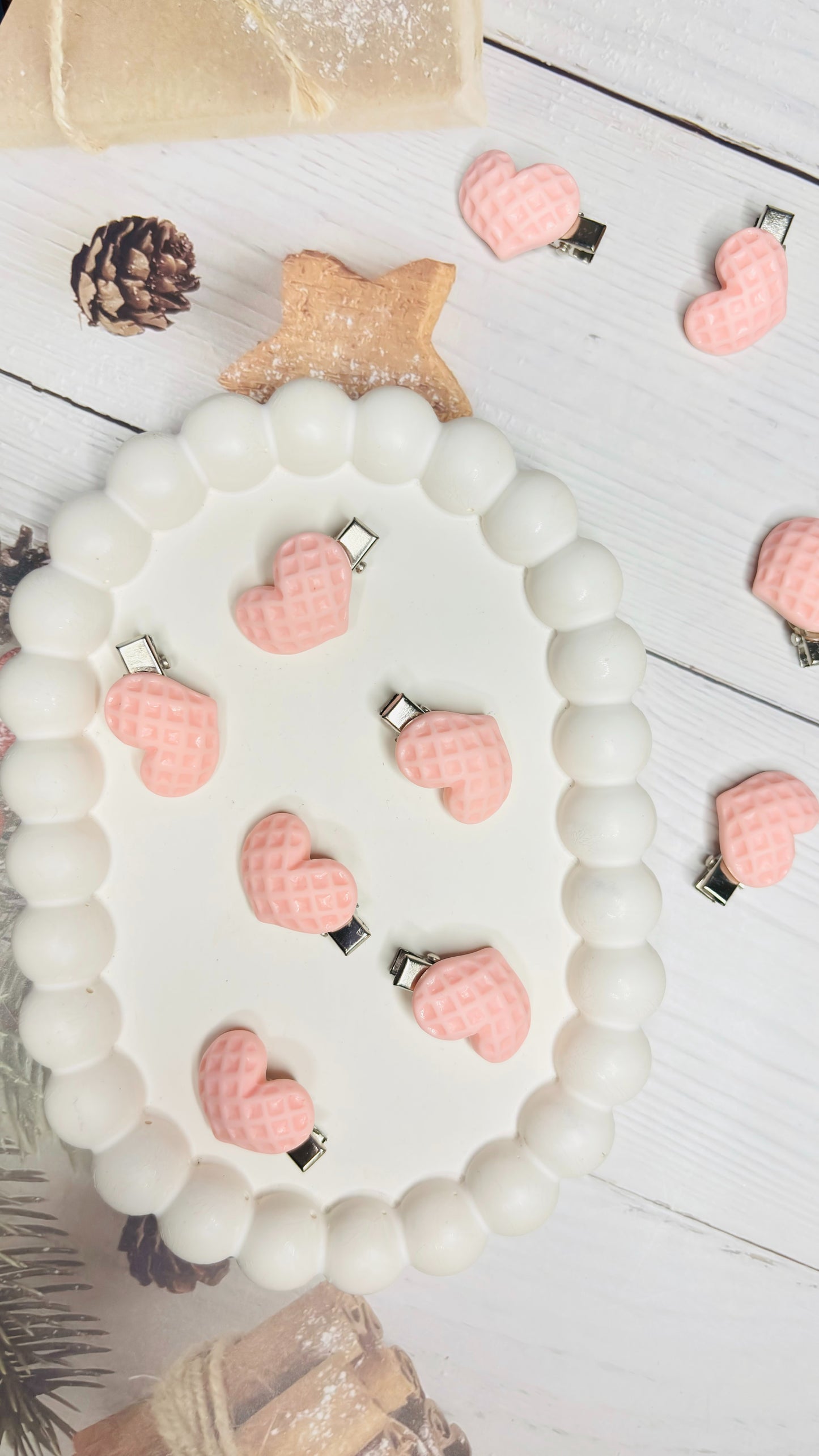 White beaded bracelet with pink heart-shaped charms on a wooden surface