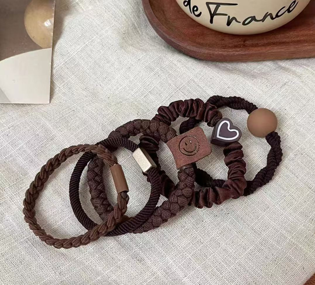 Set of brown hair ties with decorative ends on a textured fabric background