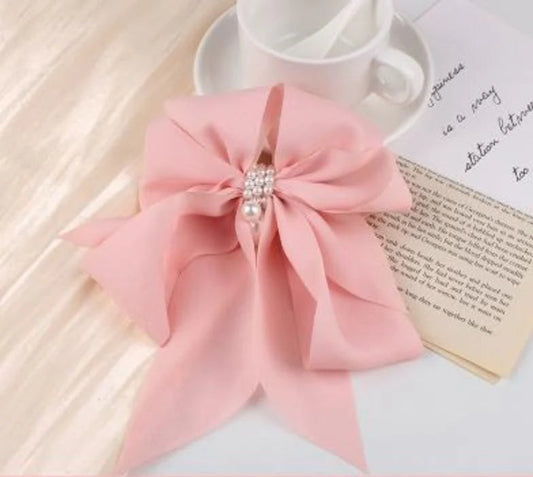 Pink bow hair clip with pearl on a white surface