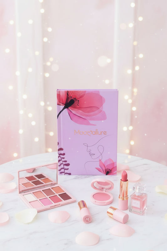 A hand with pink manicured nails holds a lavender notebook featuring a large pink hibiscus flower, a minimalist line art face, and the brand name 'Moccolure' in gold. The background is a soft-focus outdoor garden with green foliage.