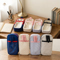 Six zippered travel pouches or small bags shown in two rows on a white background, each with a transparent front panel and a different exterior color/pattern: navy with red trim, pink with white dots, light blue with white dots, black with white grid, navy with red trim, and light blue with pink trim plus white dots.
